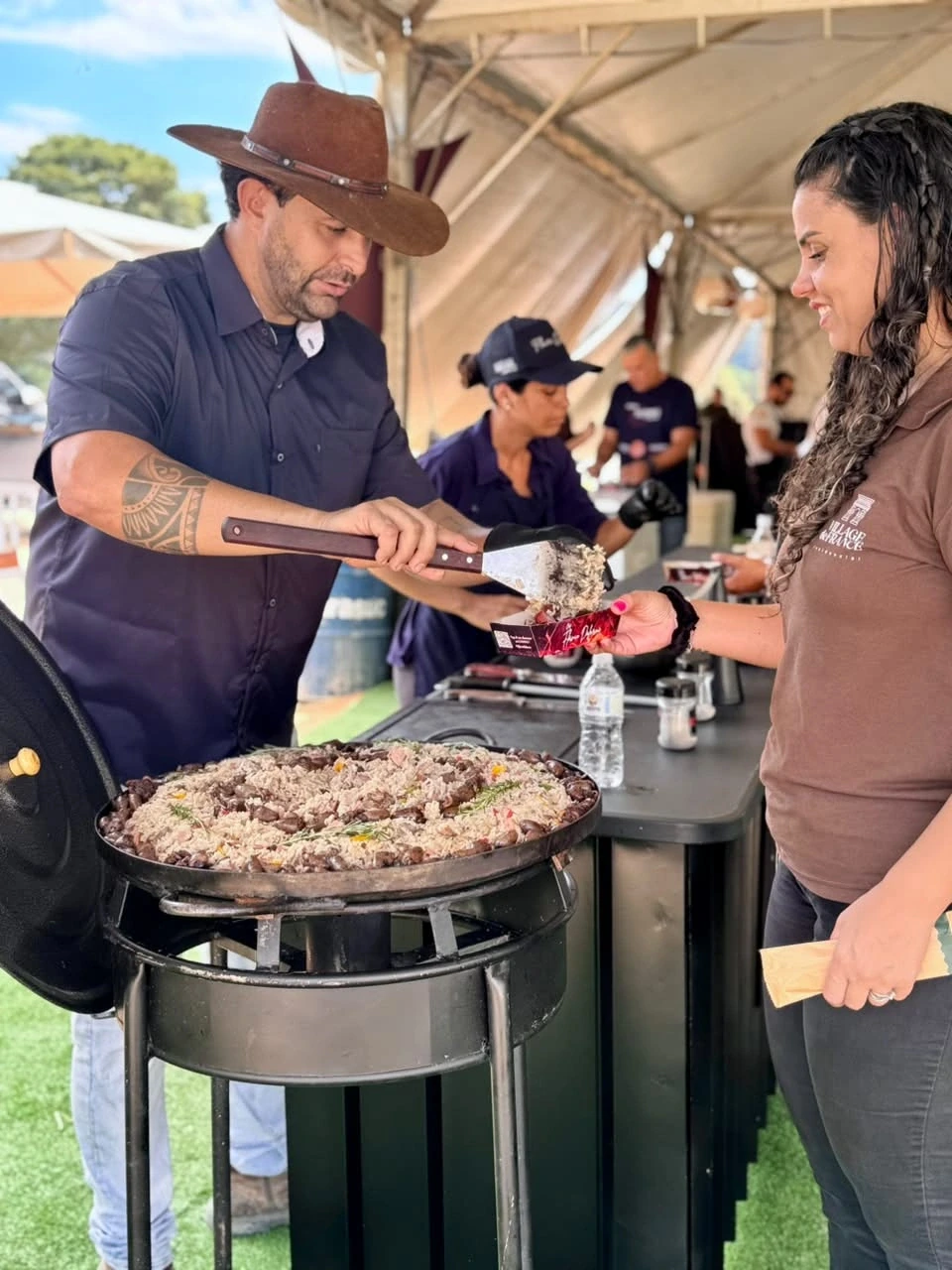 Chef Flávio servindo arroz carreteiro a uma convidada durante o evento