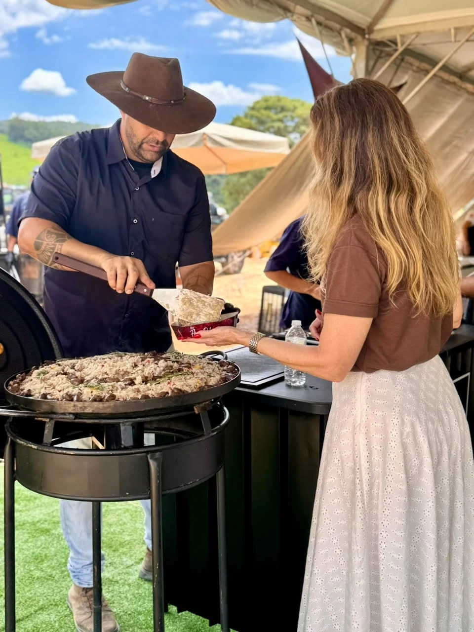 Chef Flávio servindo uma convidada diretamente na estação gastronômica